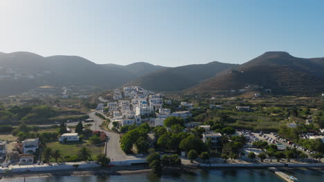 drone shot of saint george church in katapola port village on amorgos island surrounded by mountains