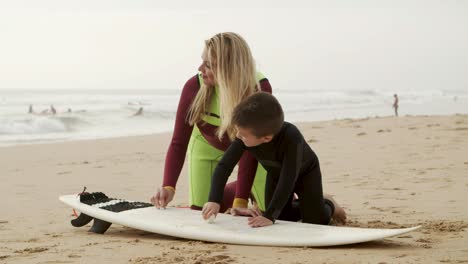 madre y hijo felices en una tabla de surf en la playa