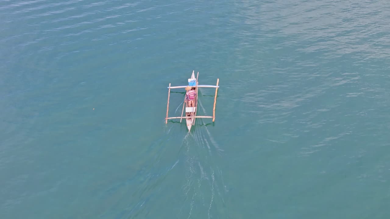 A lone fisherman floats on the calm blue waters of Leyte, Philippines, under clear skies