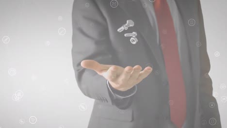 animation of media icons floating over businessman throwing and catching nuts and bolts