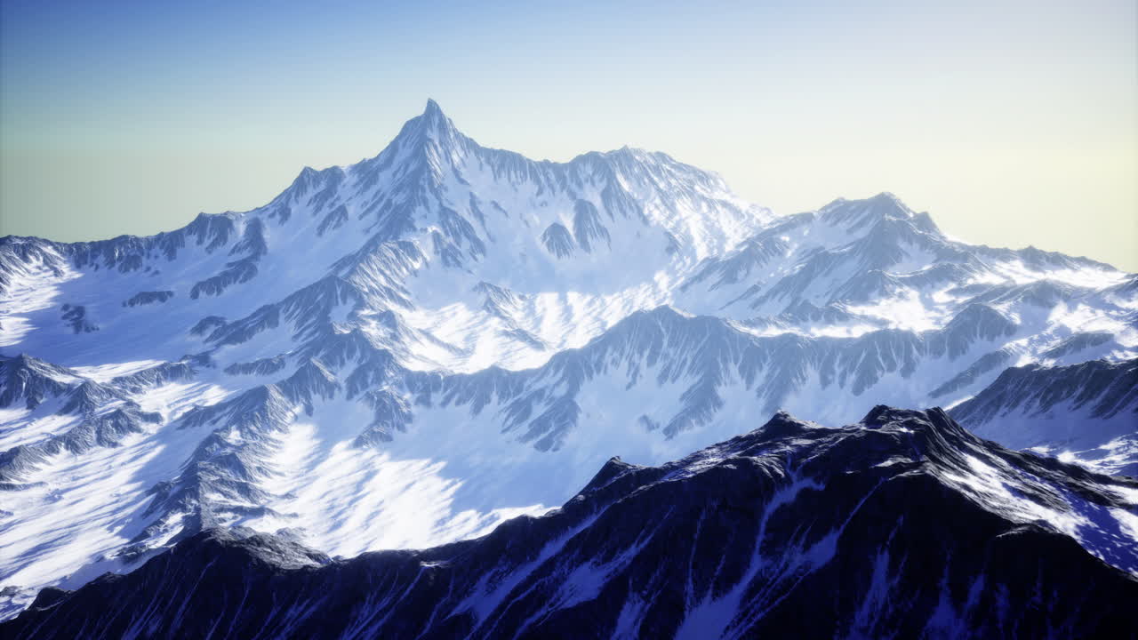 Snow covered mountain peaks at dawn with clear blue skies over valleys