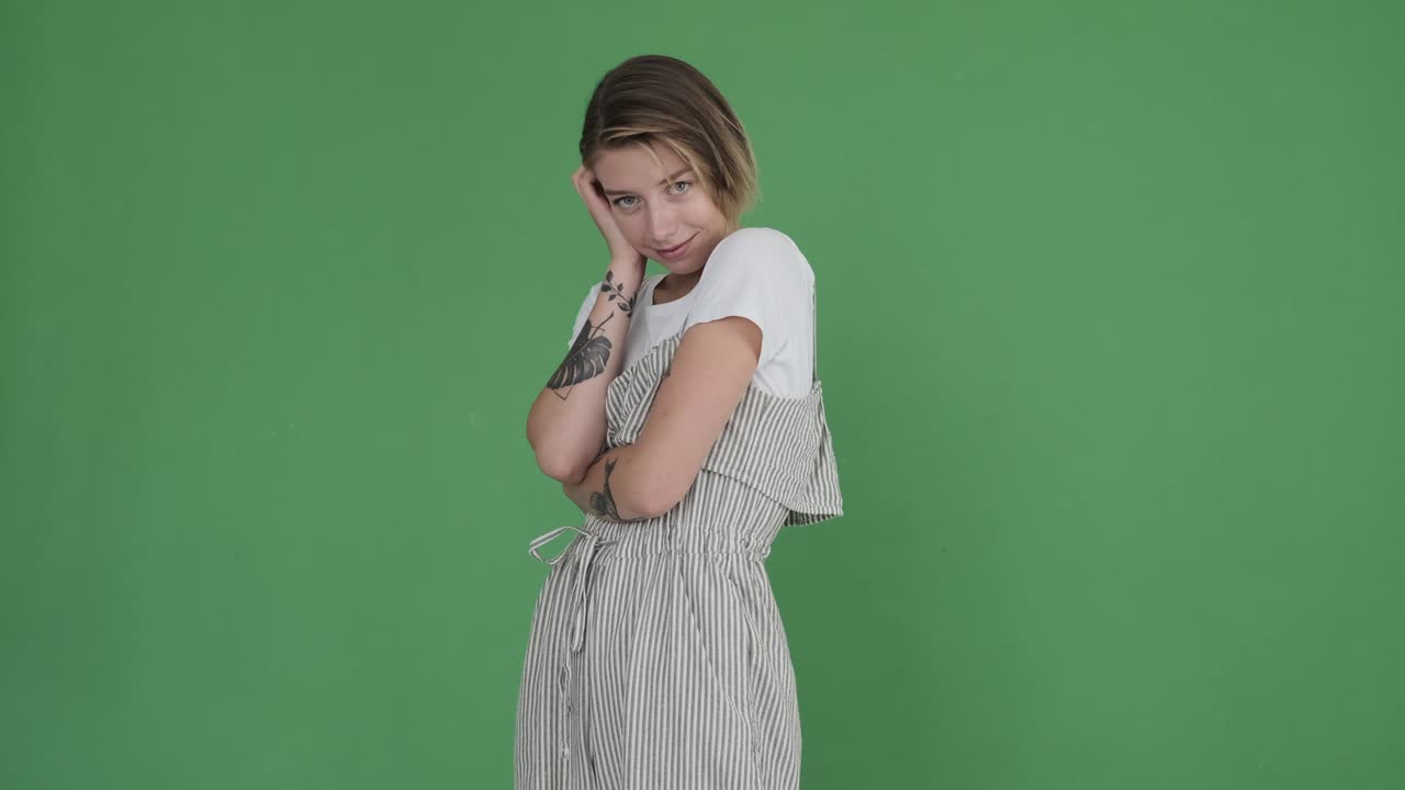 초록색 배경 에 거리 를 입고 포즈 를 취 하는 문신 된 여자