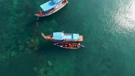 people climbing bigger boat from longtail boat clean water background