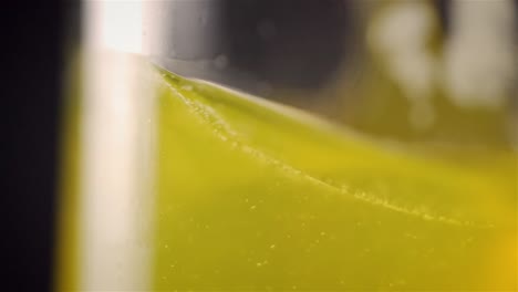 Sideview shallow depth of field of yellow drink liquid spinning around in glass in slow motion