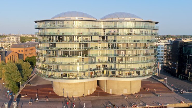 Copenhague, Dinamarca - 6 de agosto de 2025: vista aérea por drone da Gemini Residence, um prédio de vidro redondo e futurista construído sobre antigos silos, localizado à beira-mar de Islands Brygge