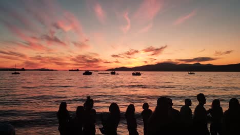 orange sunset with people silhouettes outdoors next to water sea with boats