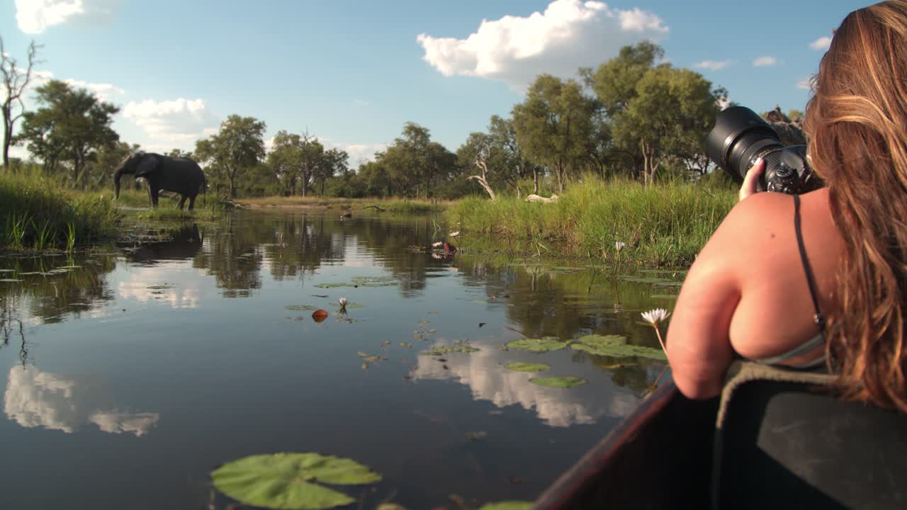 una mujer joven tomando una foto de un elefante desde un barco en un río
