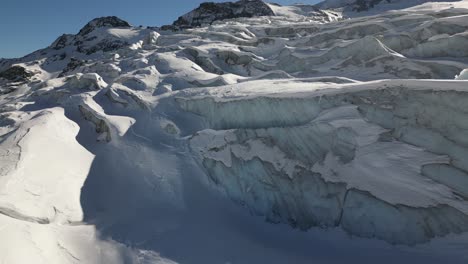 Aerial-view-of-icy-facades-in-the-Swiss-alps,-glacier-and-its-crevasses