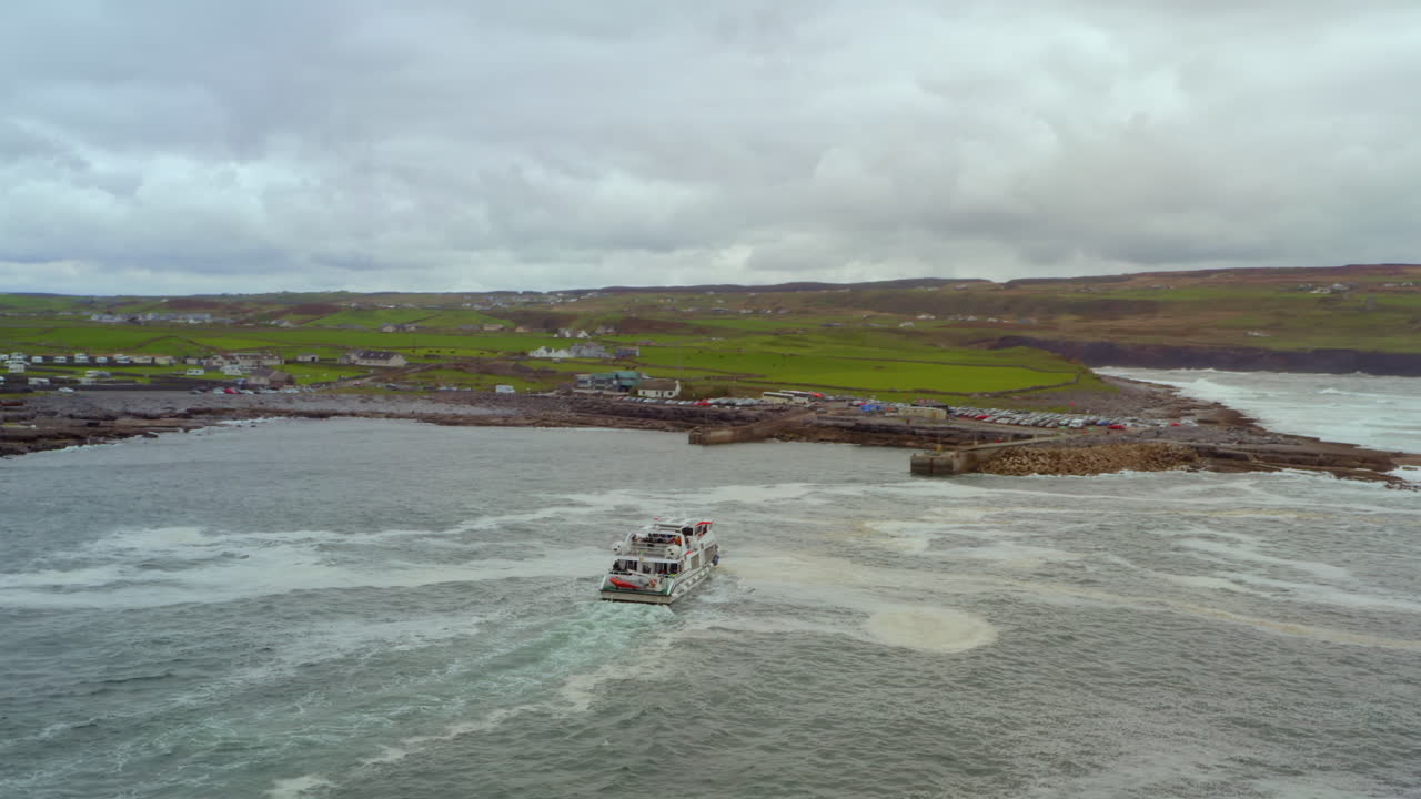 Dynamic drone orbits and ascends as the Aran Islands ferry approaches Doolin Pier, revealing the rugged coast, Cliffs of Moher, and wild Atlantic Ocean