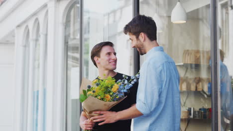 una pareja gay de hombres cariñosos tomados de la mano saliendo de la floristería con un ramo de flores