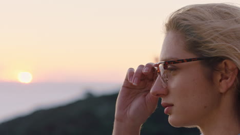 Retrato-De-Una-Mujer-Feliz-Contemplando-El-Futuro-Disfrutando-De-Un-Estilo-De-Vida-Despreocupado-Sintiéndose-Positivo-Relajándose-Mirando-El-Atardecer-Junto-Al-Mar-Con-Gafas