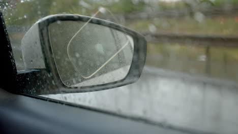 rear view mirror of driving car in rainy day