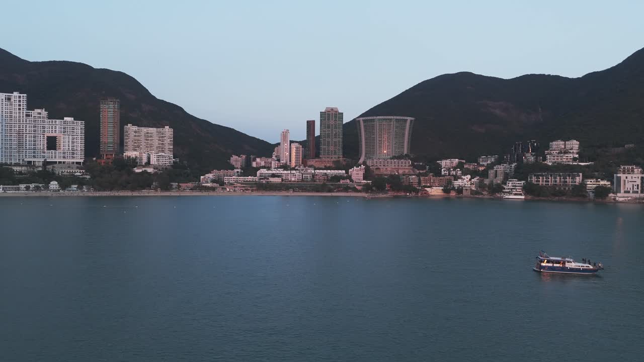 Droneoptagelse fra luften af Repulse Bay, Hong Kong, der viser sandstrand, turkisblåt vand og højhusbygninger langs kysten med panoramaudsigt over byens skyline