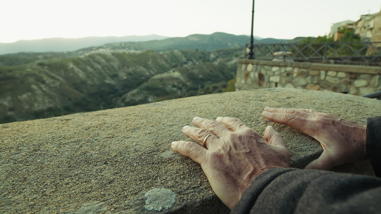 역사적인 마을에서 해가 지는 풍경에 휴식을 취하는 노인의 손