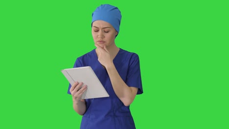 young woman doctor or nurse in scrubs using a touchscreen computer while walking on a green screen, chroma key