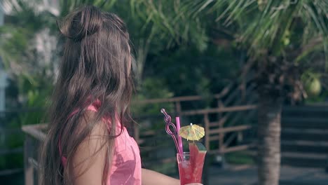 girl-holds-drink-in-hands-and-long-dark-hair-waves-slowly