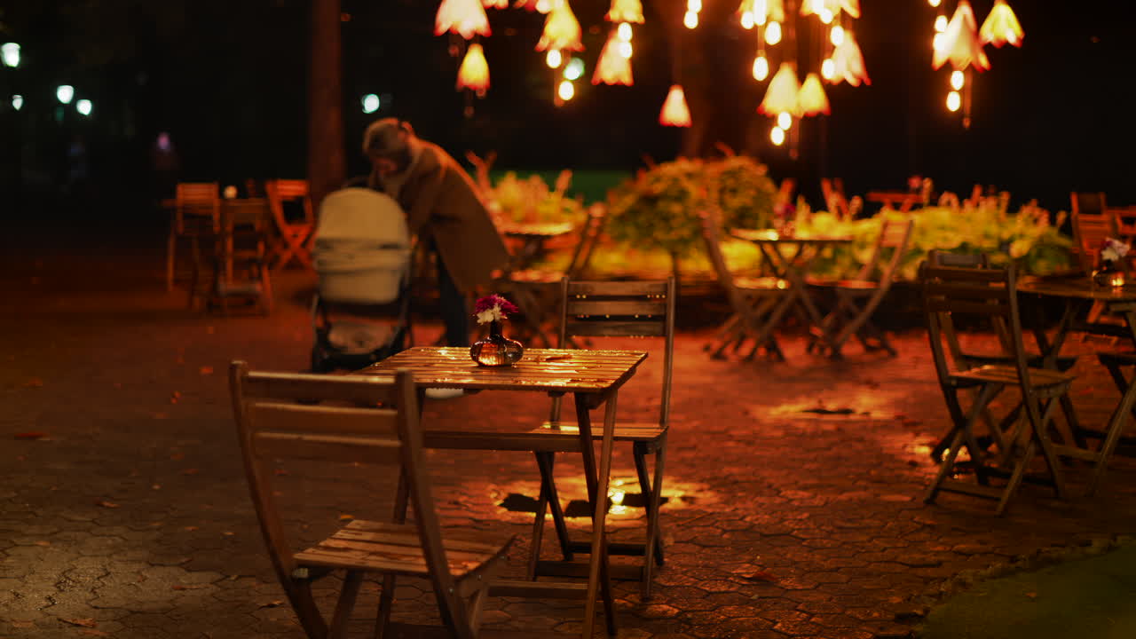 A cozy outdoor cafe at night with glowing warm lights and wooden chairs glistening after rain