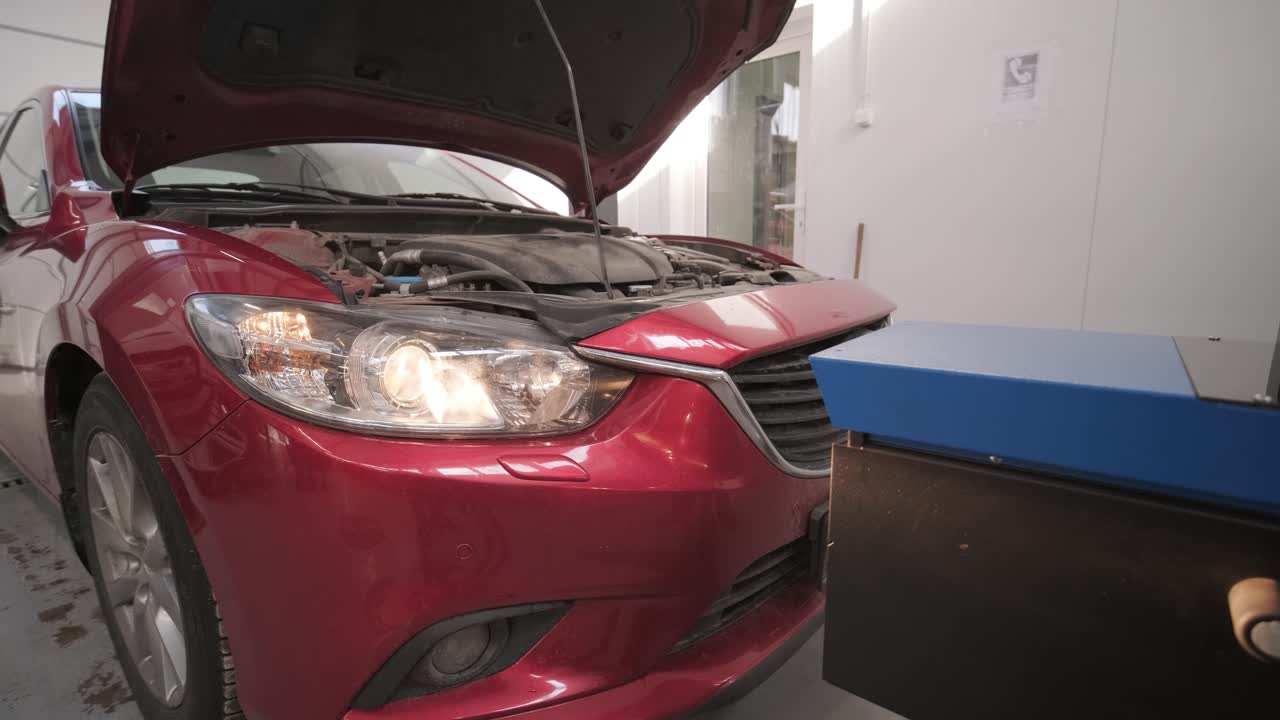 trabajador comprueba y ajusta los faros del sistema de iluminación de un automóvil. servicio de reparación de automóviles.