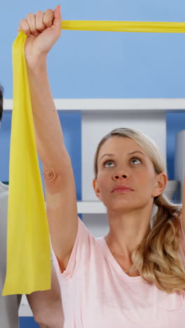 physiotherapist training female patient with exercise band