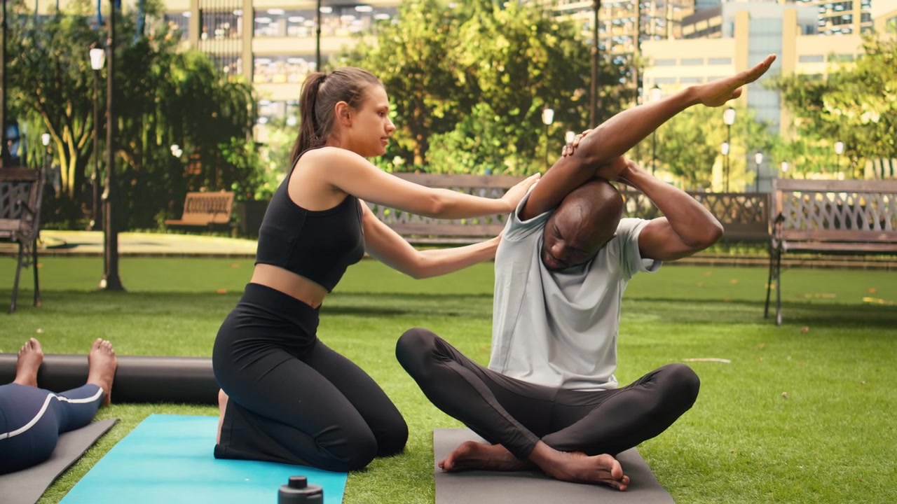 Yoga instructor guiding man through side stretch exercise