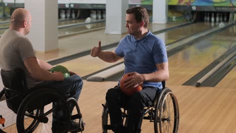 two young disabled men in wheelchairs playing bowling in the club