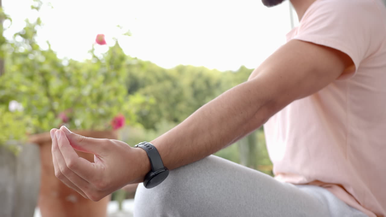 Uomo seduto a gambe incrociate all'aperto, che medita con uno smartwatch al polso