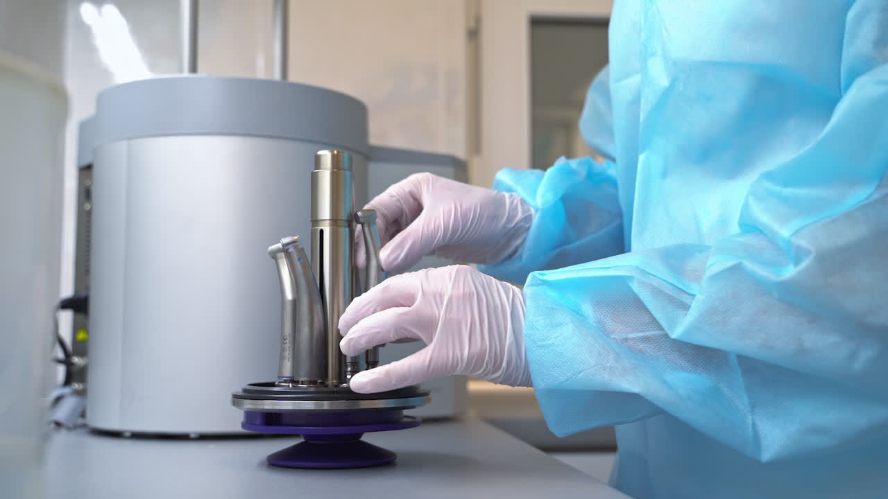 Dentistry tools are being placed on the part of the sterilizing machine. Medical worker puts the instruments into a sterilizer.