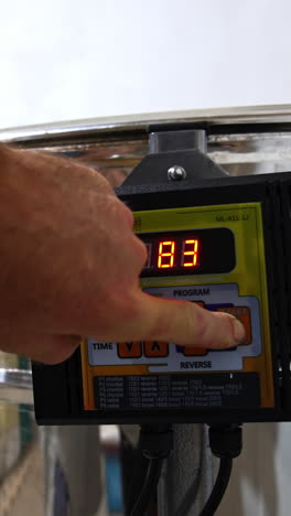 male hand switching on the button on the centrifuge apparatus. man presses one more button to increase the speed of work of equipment. close up. vertical video