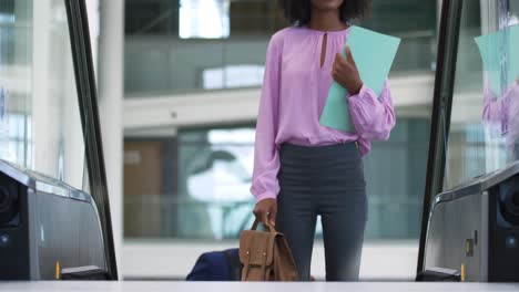 Young-businesswoman-on-an-escalator-in-a-modern-building