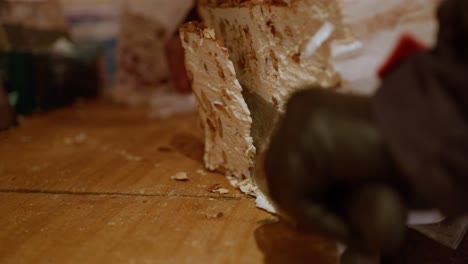 primer plano de una persona cortando un gran trozo de turrón con un cuchillo grande y dos manos