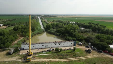 Grúa-Móvil-Amarilla-Alta-En-Un-Sitio-De-Construcción-En-Rumania-Al-Final-De-Un-Río