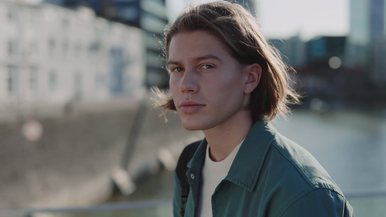 Young Man with Long Hair Looking at Camera in City