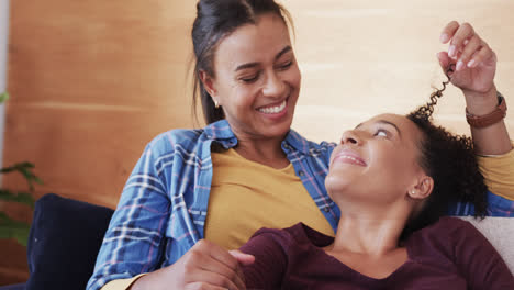 Romantic-biracial-lesbian-couple-relaxing-on-couch-together,-smiling-and-talking,-in-slow-motion