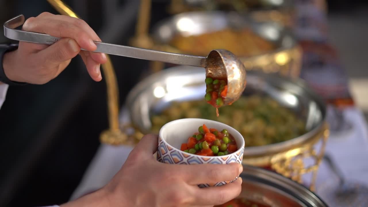 Un uomo mette dei piselli nel piatto per mangiare, primo piano, inserto.