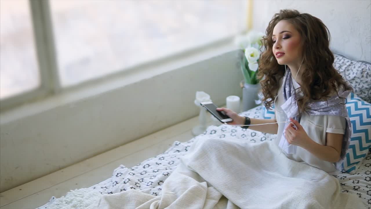 Woman relaxing on a bed listening to music