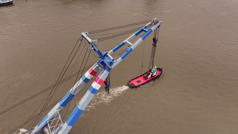 above the tug boat, intricate network of slings and pulleys of large crane