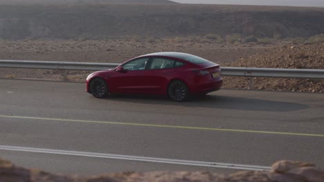 a red car on the side of the road in the desert