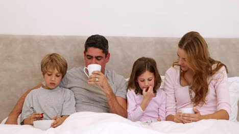 Happy-parents-and-children-having-breakfast-in-bed