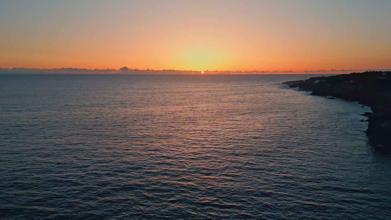 해가 지고 바다가 물결을 일으키고 해변이 공중에서 보이는 황금빛 하늘 평온한 바다 표면