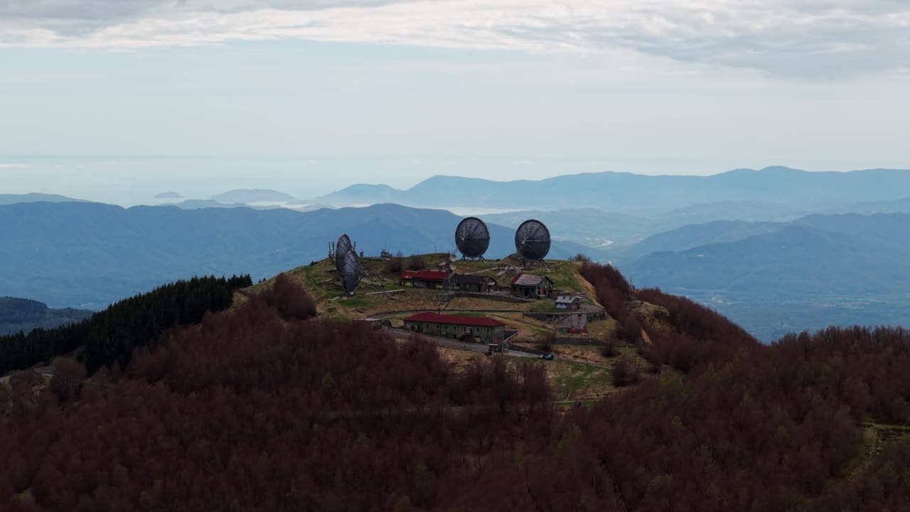 Old radar station on mountain top, wide aerial with moody weather and soft light