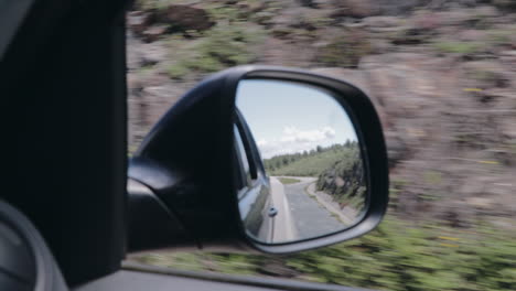 rear view through side mirror on mountain road