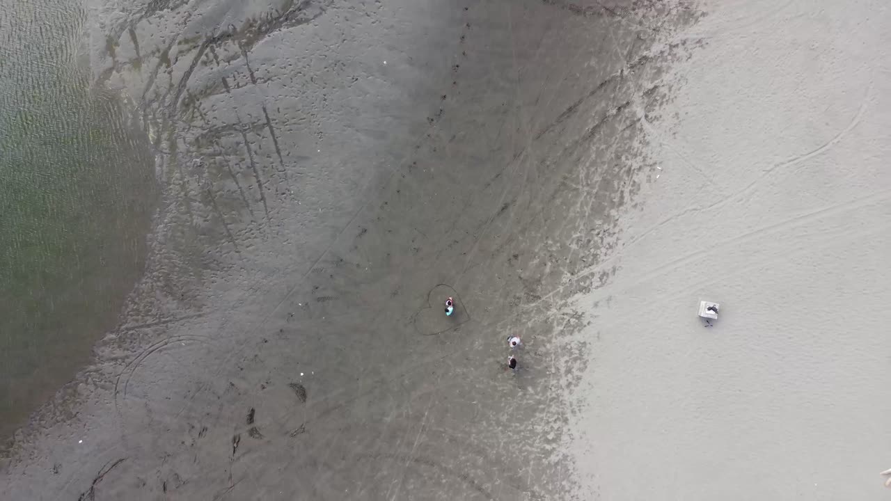 Children playing in the sand in the desert near a puddle of water. Aerial video.