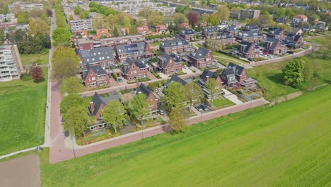 Drone-flying-away-from-a-beautiful-modern-suburban-neighborhood-with-photovoltaic-solar-panels-on-rooftop