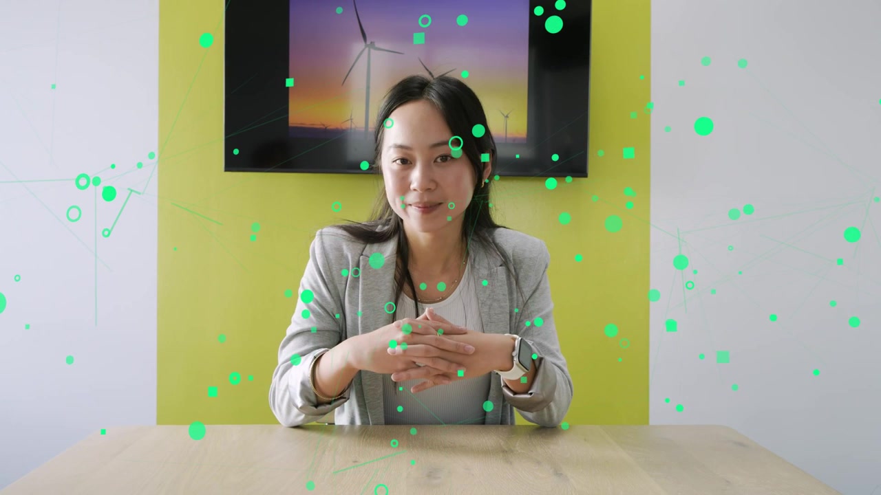 Host raising hand, gesturing, causing green particles to move while turbine screen showing energy