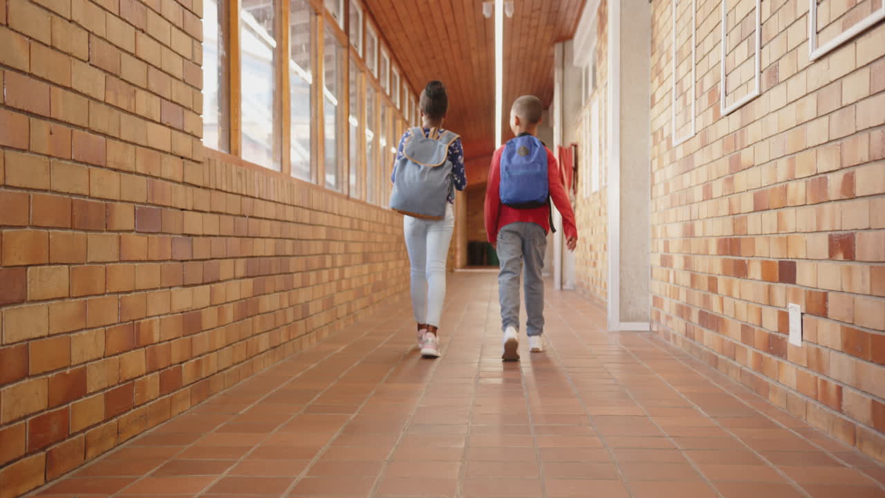 Walking in school hallway, two kids with backpacks heading to classroom