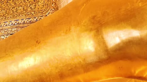 close-up view of the golden reclining buddha's serene face and detailed torso in intricate surroundings.