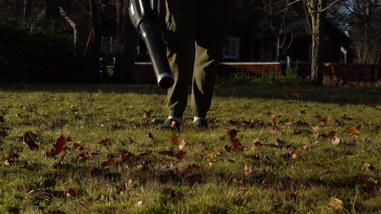 Male with a leaf blower in the evening