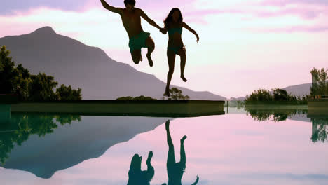 couple jumping into swimming pool holding hands