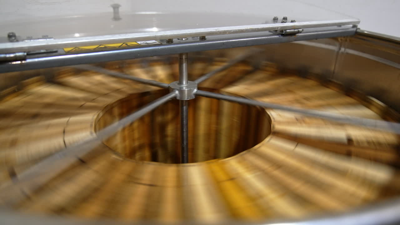 Organic honey frames spinning in the centrifuge apparatus. Special device for extracting honey at bee farms at work.