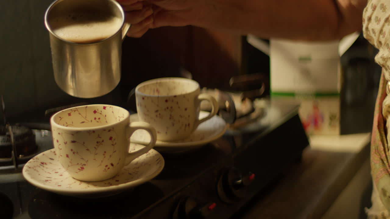 Pouring Tea into Ceramic Cups Inside a Kitchen